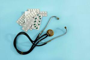 Phonendoskop und Tabletten auf ein Blau Hintergrund, medizinisch Hintergrund foto