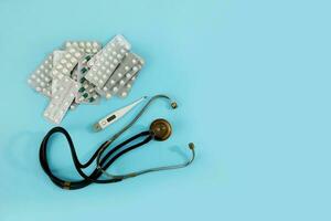 Phonendoskop Thermometer und Tabletten auf ein Blau Hintergrund, medizinisch Hintergrund mit Kopieren Raum foto