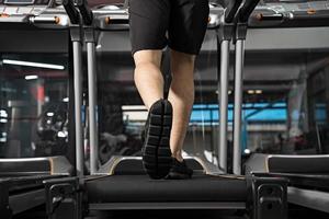 Nahaufnahme von männlichen Beinen, die auf dem Laufband im Fitnessstudio laufen? foto