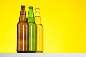 Gruppe von drei Flaschen Bier lokalisiert auf gelbem Hintergrund foto