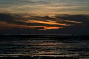 Hintergrund Silhouette Abend Sonnenuntergang von das schlammig Meer im Thailand foto