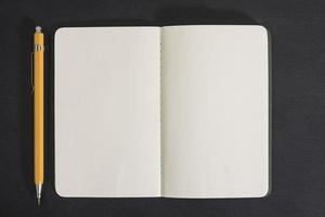 offenes Notizbuch und Bleistift auf schwarzem Hintergrund foto