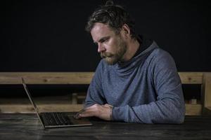 Schnurrbart-Hipster mit Bart arbeitet am Computer foto