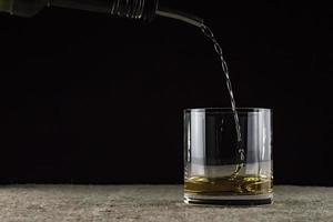 Whisky wird in ein Glas gegossen foto