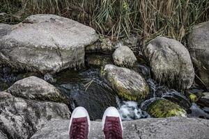 Wanderer in roten Turnschuhen am Wasserfall foto