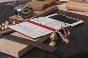Notizbuch mit Zeichnungen Bleistift Maßband Smartphone Quadrat und Flugzeug auf einem schwarzen Tisch foto