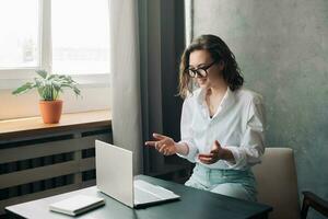 Digital Geschäft Verbindung. lächelnd jung Frau führen online Geschäft Einweisung, Umarmen Fernbedienung Arbeit wie ein jung Geschäftsfrau oder Freiberufler beschäftigt, verlobt im virtuell Zusammenarbeit auf Laptop. foto