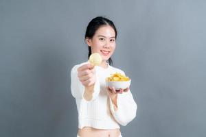 junge asiatische frau isst kartoffelchips foto