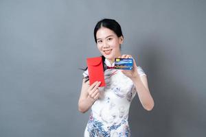 asiatische frau trägt chinesisches traditionelles kleid mit rotem umschlag oder rotem paket und kreditkarte foto