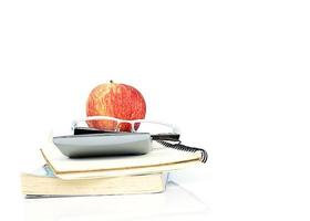rote Apfelfrucht auf Gläsern, Taschenrechner und Bücherstapel foto