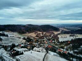 Winterlandschaft mit Dorf in der Nähe von Bergen foto