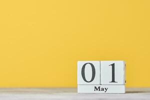 hölzern Block Kalender mit Datum kann 1 auf das Gelb Hintergrund. Arbeit Tag Konzept foto