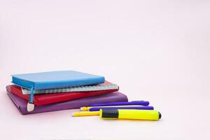 Stapel von Notizblöcke mit Stift und Marker auf Rosa Tisch. zurück zu Schule. Kopieren Raum foto