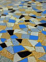 glänzend schwarz-orange blau-weiß gefliester Mosaik-Pflasterboden