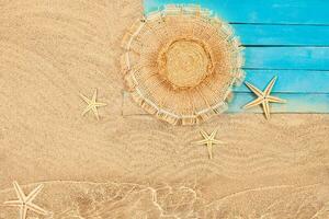 eben legen Komposition mit Strand Zubehör auf hölzern Seebrücke durch Wasser. Stroh Hut, Seestern und Blau Bretter durch Meer auf Sand. Sommer, Urlaub, Tourismus im heiß Land. Kopieren Raum foto