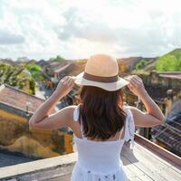 glücklich Reisender Reisen beim hoi ein uralt Stadt, Dorf im Vietnam, Frau mit Kleid und Hut Besichtigung Aussicht beim Dach.Wahrzeichen und Beliebt zum Tourist Sehenswürdigkeiten. Vietnam und Süd-Ost Asien Reise Konzept foto