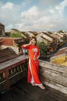 glücklich Frau tragen ao dai Vietnamesisch Kleid, Reisender Besichtigung Aussicht beim Dach beim hoi ein uralt Stadt, Dorf im Vietnam. Wahrzeichen und Beliebt zum Tourist Sehenswürdigkeiten. Vietnam und Süd-Ost Reise Konzept foto