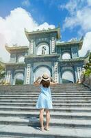 Frau Reisender Besuch beim Linh ung Pagode Tempel, Übersetzung von Chinesisch Charakter. Tourist mit Blau Kleid und Hut Reisen im da nang Stadt. Vietnam und Süd-Ost Asien Reise Konzept foto