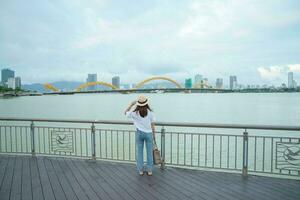 Frau Reisender Besuch im da nang Stadt. Tourist Besichtigung das Fluss Aussicht mit Drachen Brücke. Wahrzeichen und Beliebt zum Tourist Attraktion. Vietnam und Süd-Ost Asien Reise Konzept foto