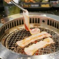Hand Grillen Fleisch Schweinefleisch auf Herd Dienen im Restaurant. japanisch Essen und Koreanisch Grill traditionell Stil foto