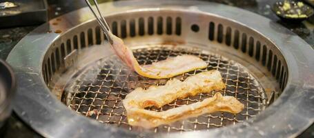 Hand Grillen Fleisch Schweinefleisch auf Herd Dienen im Restaurant. japanisch Essen und Koreanisch Grill traditionell Stil foto