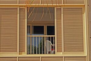 Hintergrund mit ein Fenster und Balkon umgeben durch ein hölzern blind auf ein warm Sommer- Tag foto