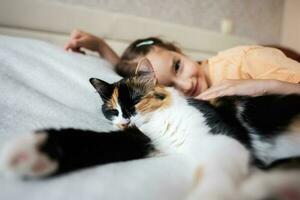 Porträt von ein wenig Mädchen mit Katze Lügen auf das Bett beim Zuhause foto