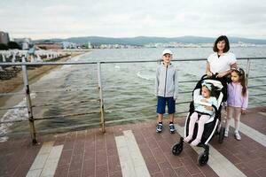 glücklich Mutter mit drei Kinder auf das Promenade durch das Meer im sonnig Strand, Bulgarien. foto