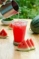 Wassermelone Saft Gießen im ein Glas auf hölzern Tabelle foto