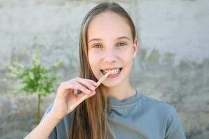 ein Mädchen Bürsten ihr Zähne siwak Stock. miswak Stöcke. foto