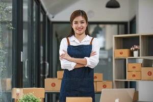 Porträt einer asiatischen jungen Frau, die zu Hause mit einer Kiste am Arbeitsplatz arbeitet. Start-up-Kleinunternehmer, Kleinunternehmer-KMU oder freiberufliches Online- und Lieferkonzept. foto
