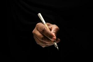 asiatisch männlich dunkel gehäutet Single Hand Faust Finger auf schwarz Hintergrund halten Stift schreiben Zeichen foto