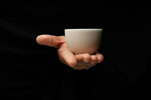 asiatisch männlich dunkel gehäutet Single Hand Faust Finger auf schwarz Hintergrund halten Weiß japanisch Chinesisch Teetasse foto