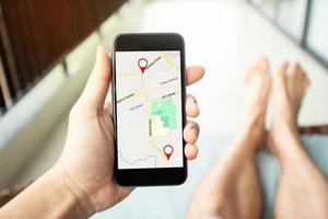 Mannhand, die Smartphone mit GPS-Karte zum Routenziel hält foto