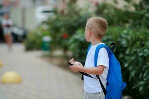 ein Junge mit ein Aktentasche auf seine zurück geht zu Schule. zurück zu Schule. sicher Straße zu Schule. foto