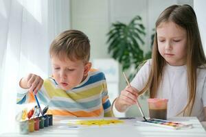 Bruder und Schwester zeichnen ein Bild mit Farben auf ein Stück von Papier. Kinder sind Lernen zu ziehen. Zuhause Kreativität. foto