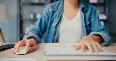 freiberufliche asiatische Dame Freizeitkleidung mit Desktop-Computer online lernen im Wohnzimmer zu Hause foto