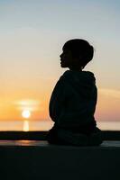 schön Sonnenuntergang auf das Meer mit das Silhouette von ein Kind auf das Hintergrund foto