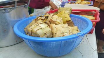Ketupat ist indonesisches traditionelles Essen. Ketupat ist Reiskuchen, der in einem rautenförmigen Paket aus geflochtenen jungen Kokosnussblättern gekocht wird. foto