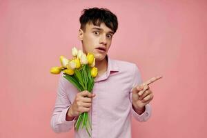 ein jung Mann Strauß von Gelb Blumen Romantik posieren Mode Rosa Hintergrund unverändert foto