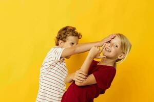 zwei froh Kinder kuscheln Mode Kindheit Unterhaltung Gelb Hintergrund foto