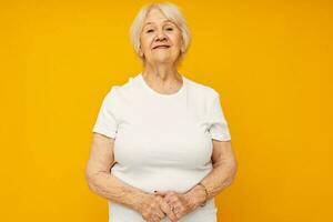 Foto von im Ruhestand alt Dame im beiläufig T-Shirt Gesten mit seine Hände Gelb Hintergrund