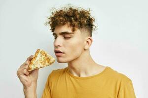 gut aussehend Kerl im ein Gelb T-Shirt Essen Pizza isoliert Hintergrund foto