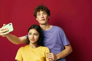 ein jung Paar im bunt T-Shirts mit ein Telefon isoliert Hintergrund foto