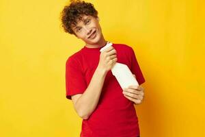 Porträt von ein jung lockig Mann im ein rot T-Shirt Waschmittel im Hände posieren Lebensstil unverändert foto