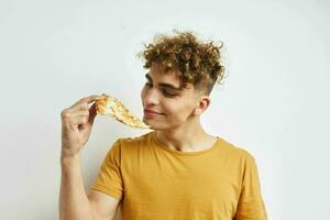 gut aussehend jung Mann im ein Gelb T-Shirt Essen Pizza Lebensstil unverändert foto