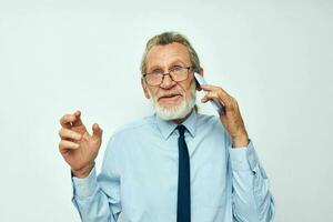 Senior grauhaarig Mann im ein Hemd mit ein Krawatte mit ein Telefon Technologie abgeschnitten Aussicht foto