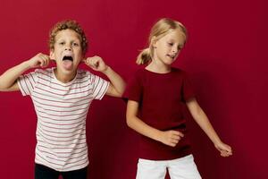 süß stilvoll Kinder Emotionen Stand Seite durch Seite im täglich Kleider rot Hintergrund foto