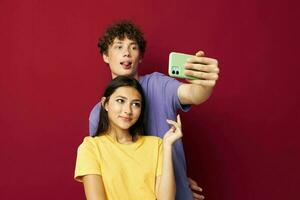 Mann und Frau im bunt T-Shirts mit ein Telefon isoliert Hintergrund foto