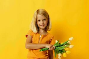 wenig Mädchen mit blond Haar mit ein Strauß von Gelb Blumen auf ein Gelb Hintergrund foto